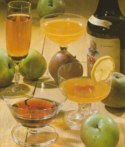 Verschiedene Cocktails und Aperitifs in eleganten Gläsern, umgeben von frischen grünen Äpfeln. Im Hintergrund eine Calvados-Flasche.