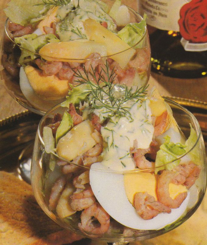 Zwei Glasschalen gefüllt mit Krabben-Cocktail, bestehend aus Nordseekrabben, Salatblättern, Eierscheiben, Spargelstücken und einer hellen Sauce, garniert mit frischem Dill.